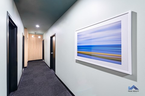 A hallway with a painting on the wall and a carpet on the floor.