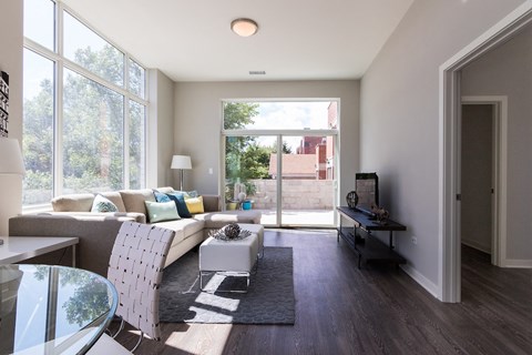 A modern living room with a glass table and a grey sofa.