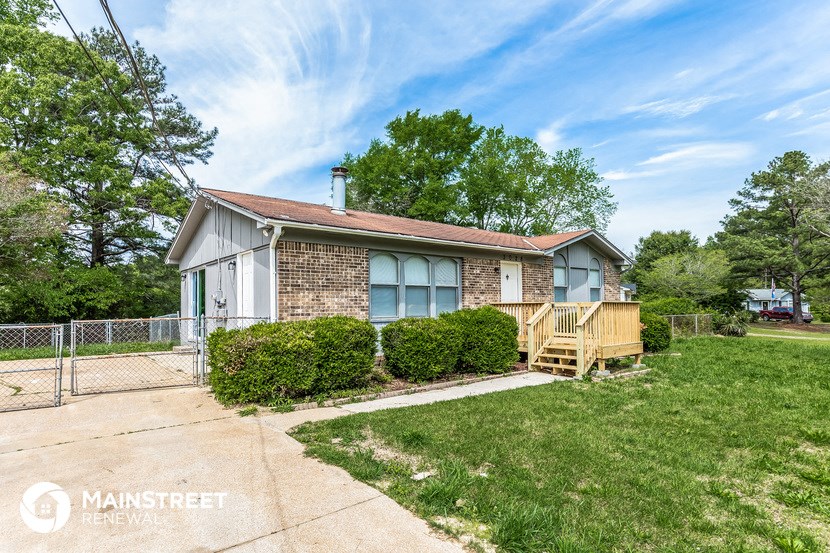 a small brick house with a deck and a fence