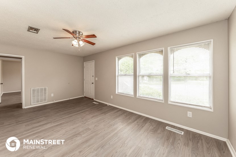 the living room of this home has a large window and a ceiling fan
