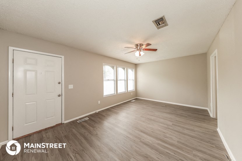 the spacious living room with a ceiling fan and wood flooring