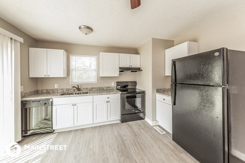 a kitchen with white cabinets and a black refrigerator