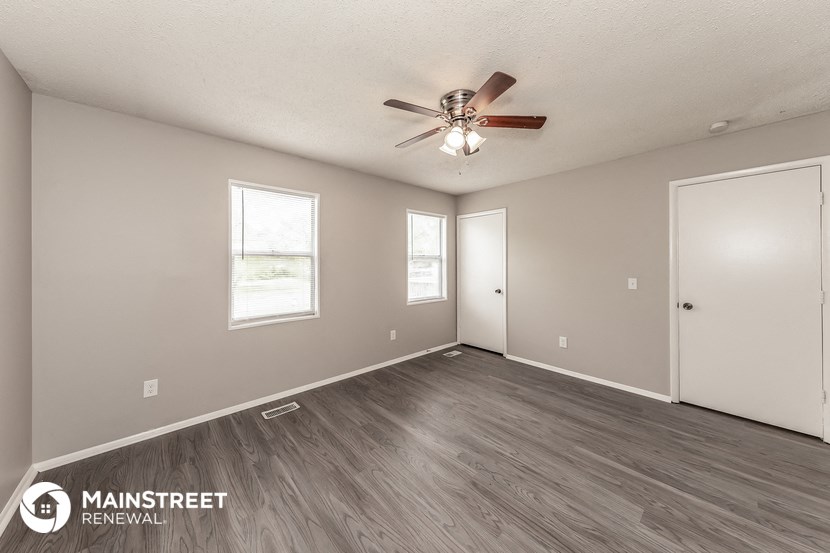 the spacious living room with ceiling fan and wood flooring