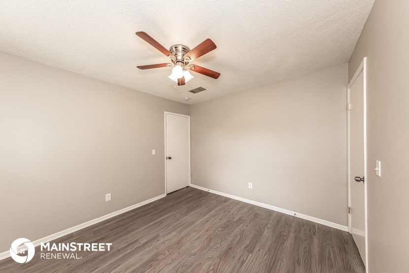 the spacious living room with ceiling fan and wood flooring