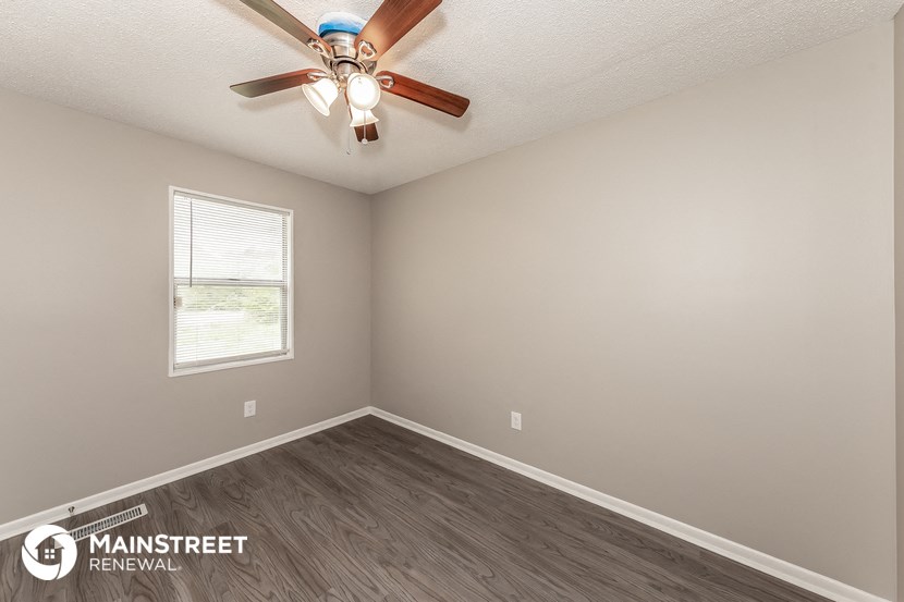 the spacious living room with ceiling fan and wood flooring