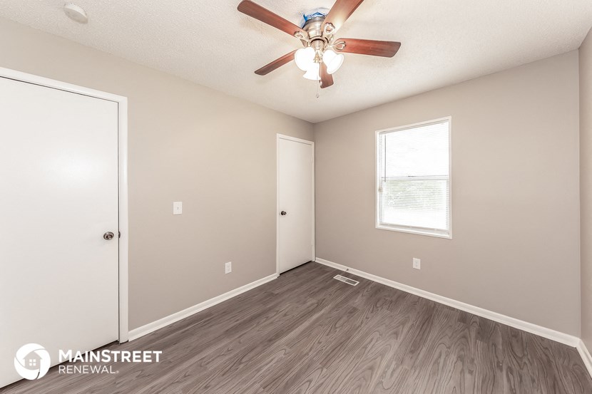 the spacious living room with ceiling fan and wood flooring