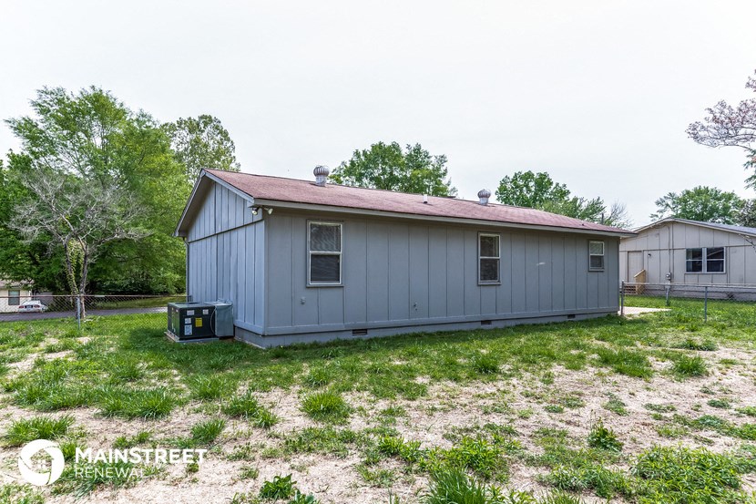the view of the backyard of a small blue house with a yard and grass