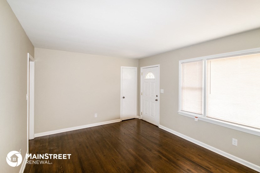 the living room of a home with wood flooring and a white door