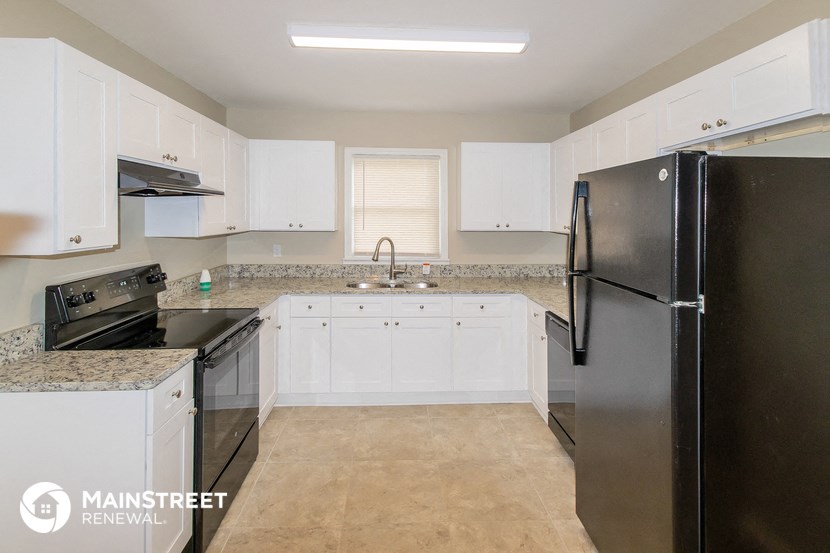 a kitchen with white cabinets and black appliances and a stainless steel refrigerator