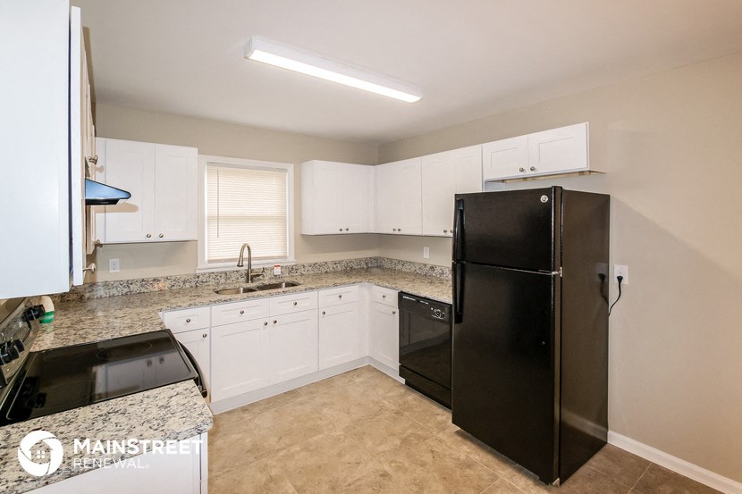 a kitchen with white cabinets and a black refrigerator