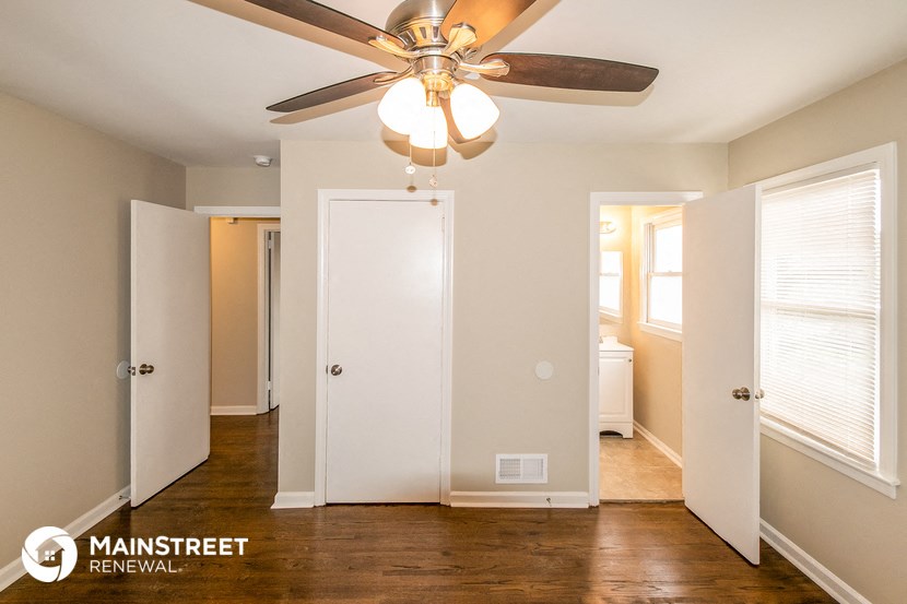 a bedroom with a ceiling fan and a hallway with two doors