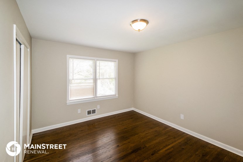 the interior of a bedroom with wood flooring and a window