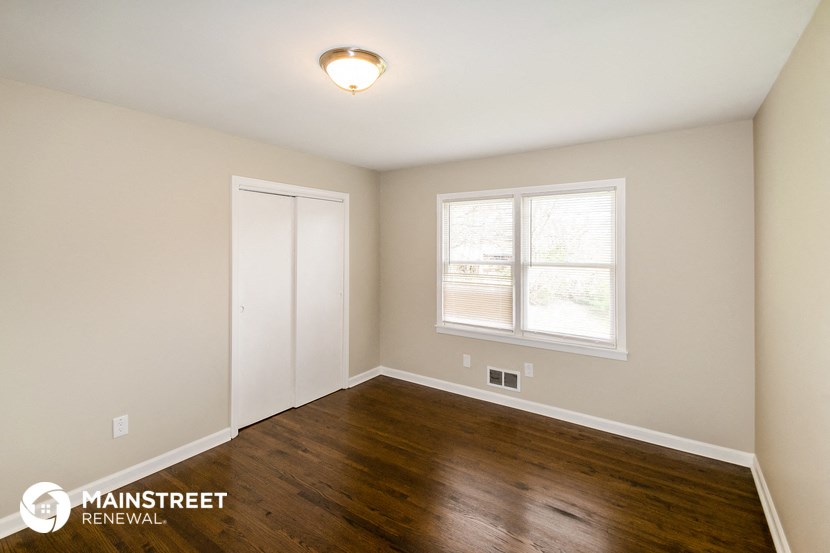 the spacious living room with hardwood flooring and a window