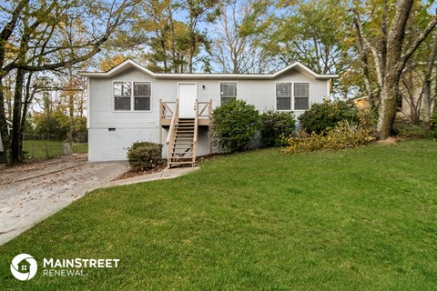 a small white house with a yard and a staircase