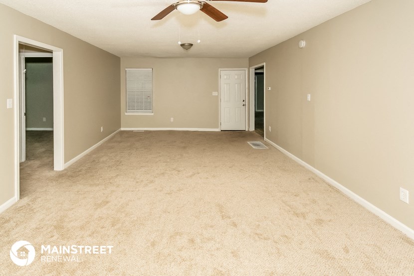 a empty living room with a ceiling fan and a door