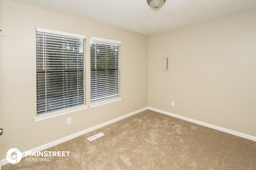 an empty room with two windows and a carpeted floor