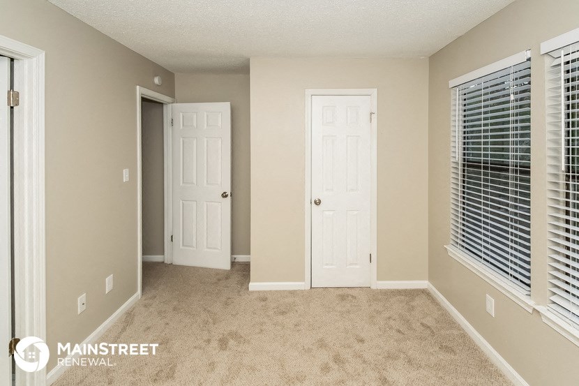 the spacious living room with two doors to the closet and a window