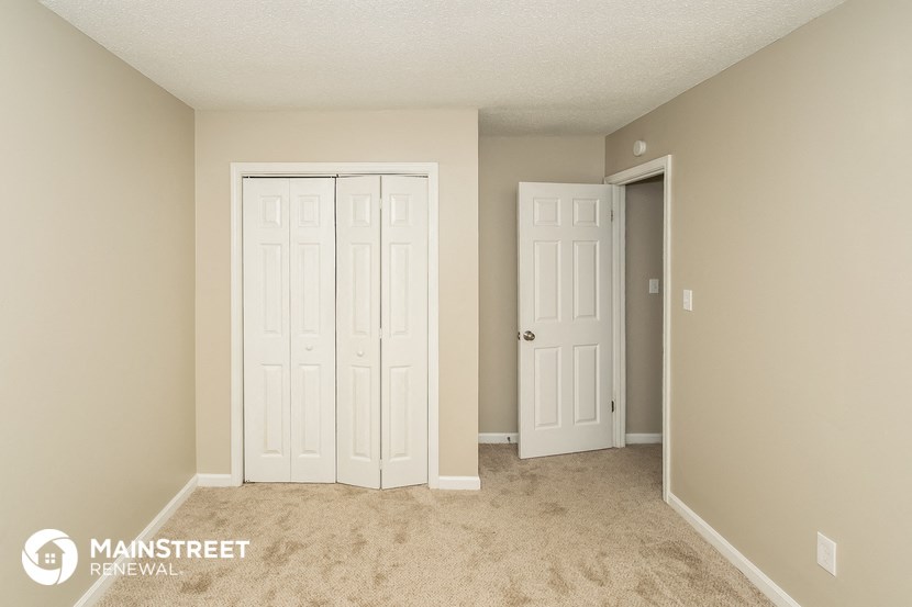 a bedroom with two white doors and a carpeted floor