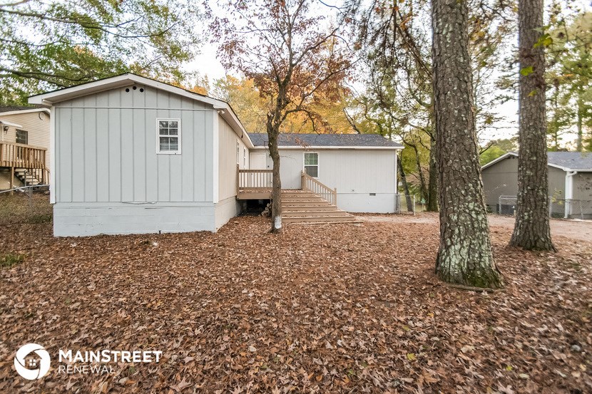 a small white house in the middle of a yard with trees