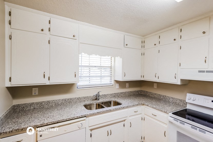 a kitchen with white cabinets and granite counter tops and a sink