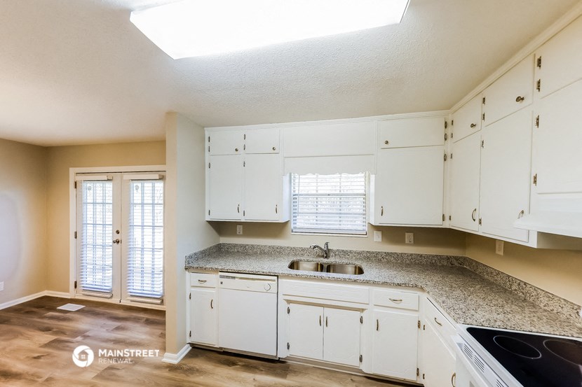an empty kitchen with white cabinets and granite counter tops