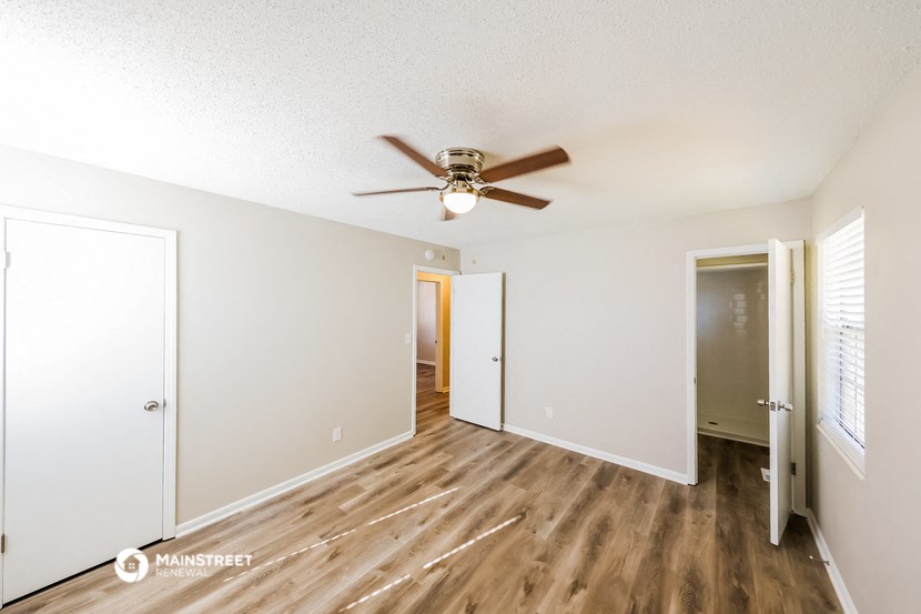 a living room with a ceiling fan and a door to a hallway