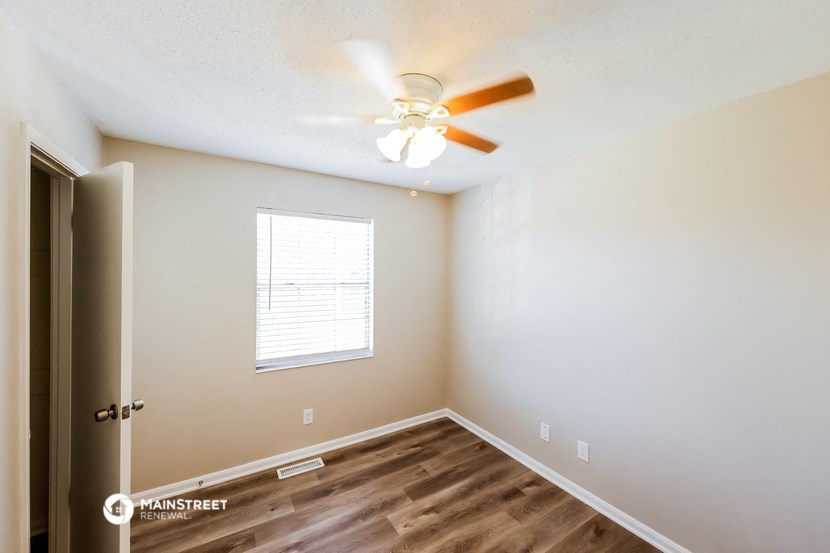 an empty room with a ceiling fan and a window
