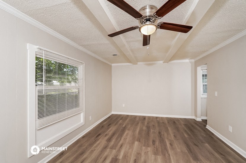 an empty living room with a ceiling fan and a window