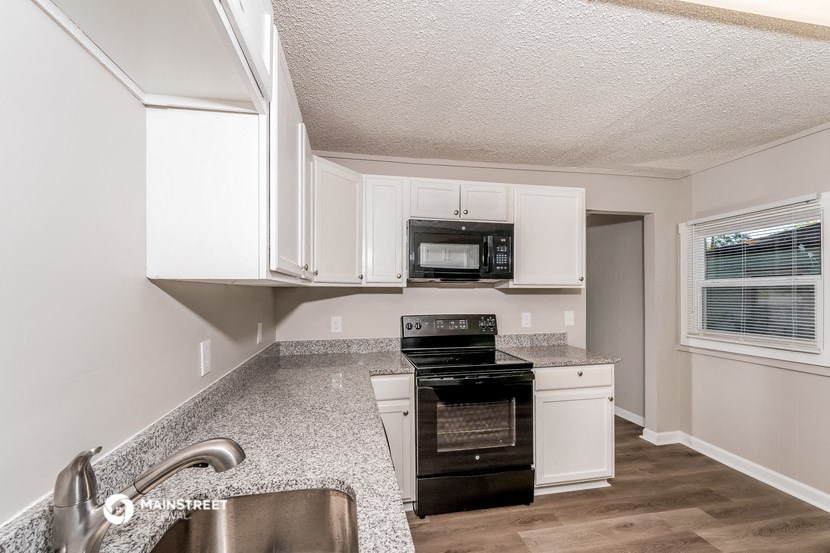 a kitchen with white cabinets and black appliances and a sink