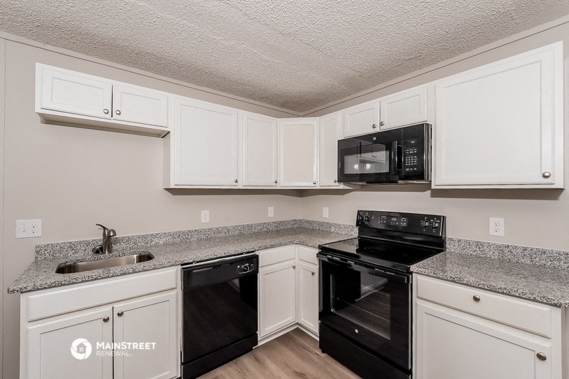 a kitchen with white cabinets and black appliances and granite counter tops