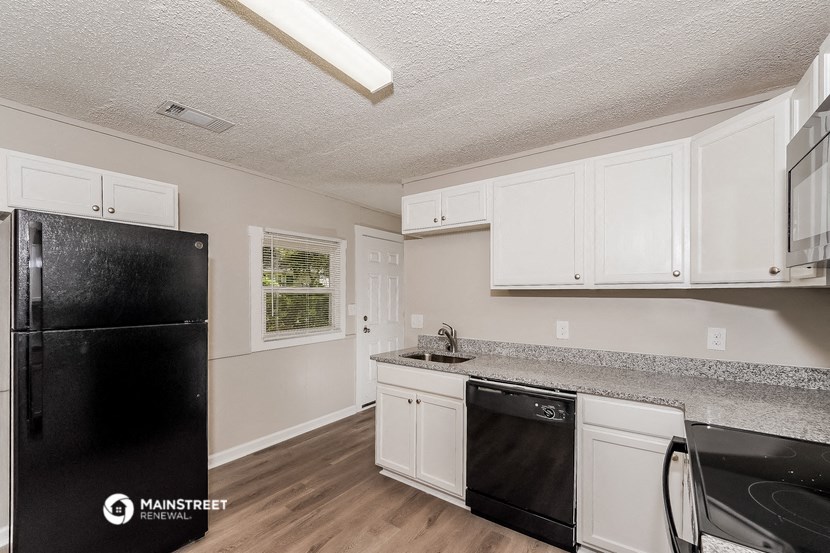 a kitchen with white cabinets and a black refrigerator