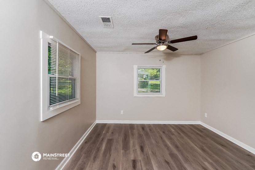 an empty living room with a ceiling fan and a window
