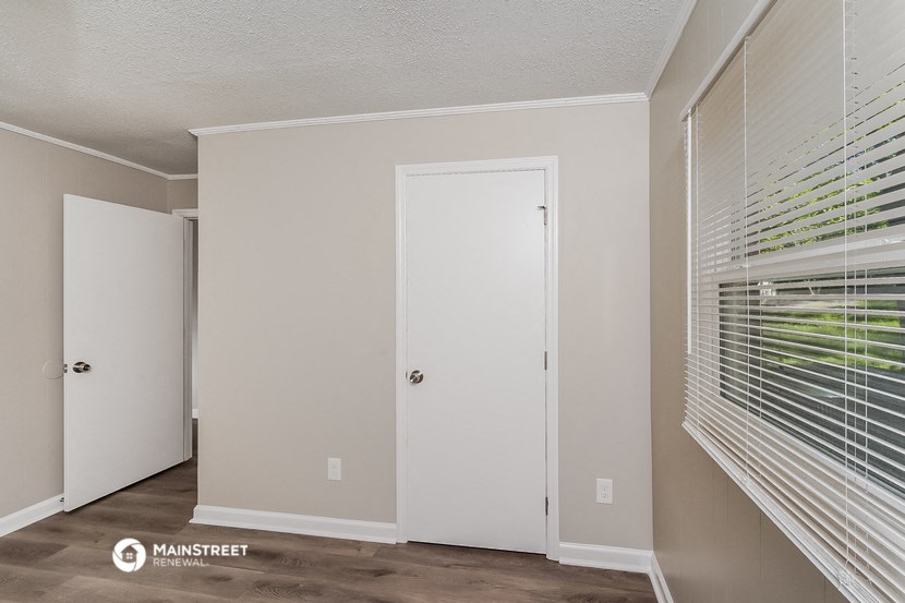 a bedroom with a large window and a door to a closet