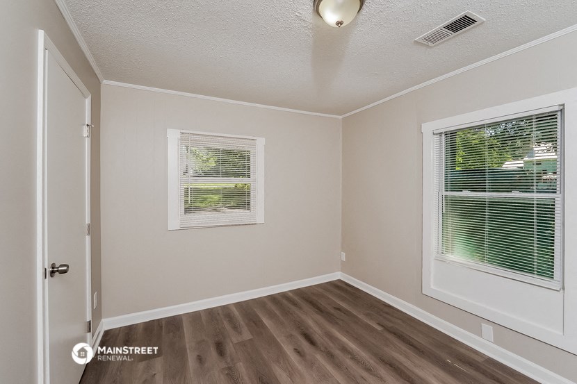 the interior of an empty room with wood flooring and a window