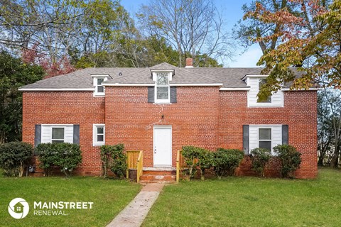 a brick house with a white front door and a lawn
