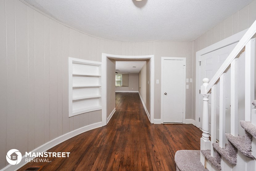 a view of the hallway of a house with white walls and wood floors