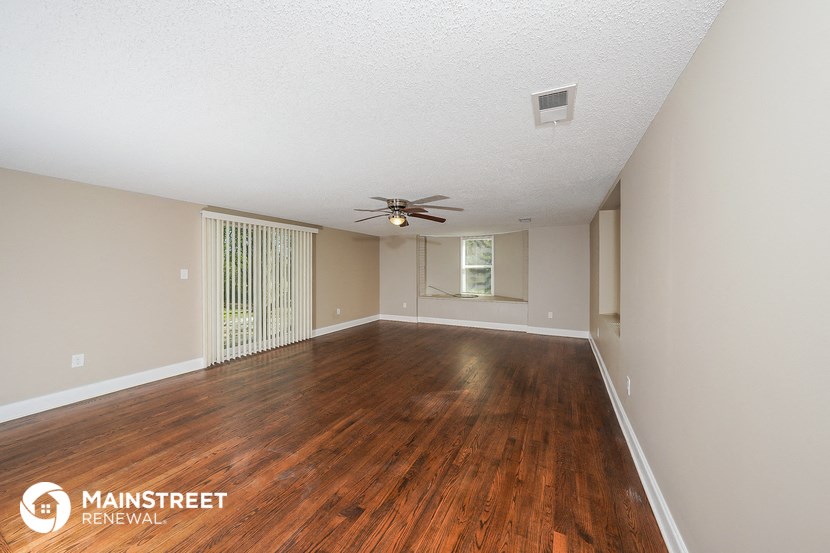 an empty living room with wood flooring and a ceiling fan