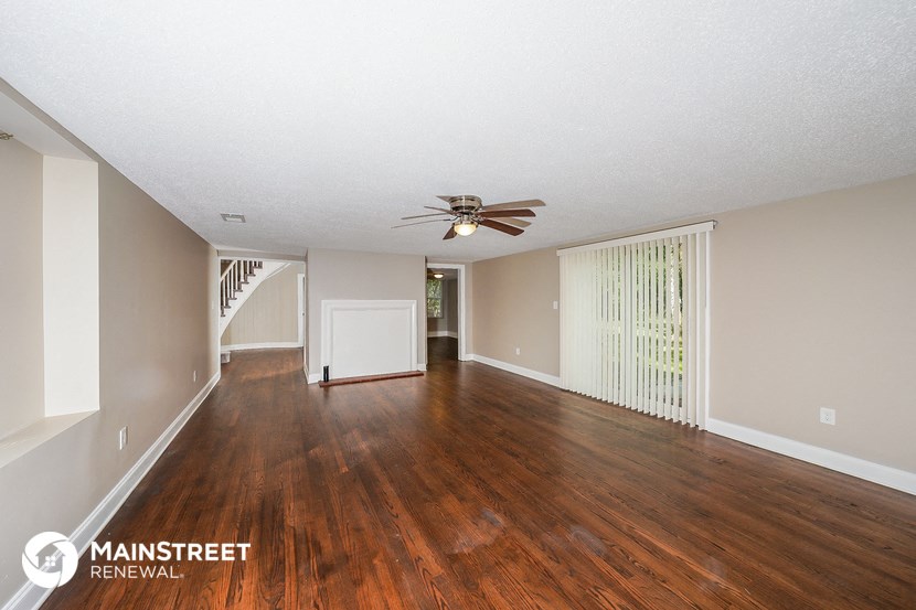 an empty living room with wood floors and a ceiling fan