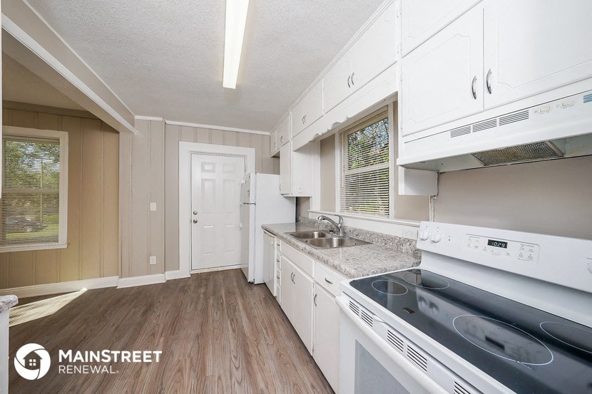 a kitchen with white cabinets and white appliances and a sink