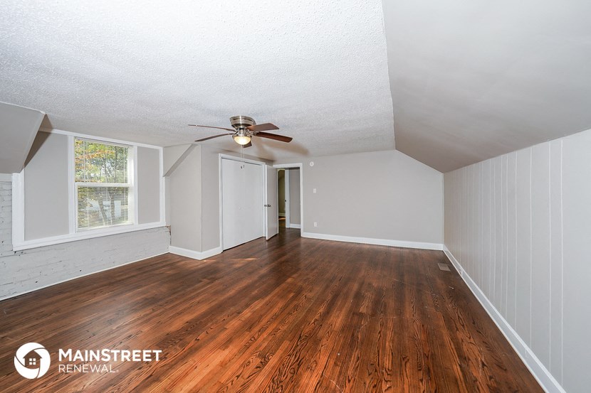 the living room and dining room with wood floors and a ceiling fan