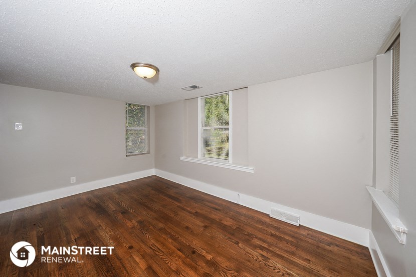 the living room of a house with wood floors and white walls