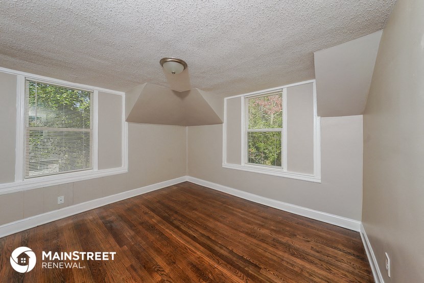 the living room of a home with wood floors and white walls