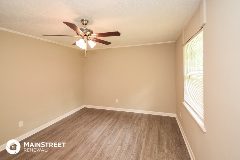 the spacious living room with wood flooring and a ceiling fan