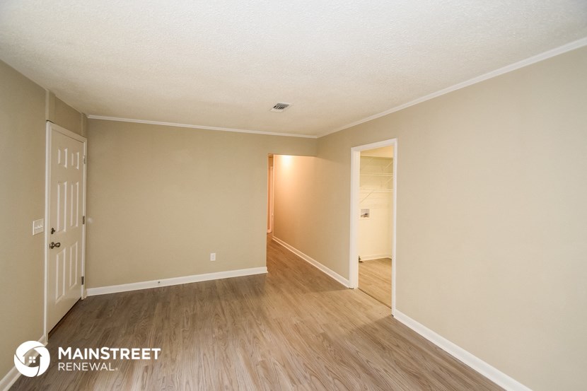 the spacious living room with wood flooring and white walls