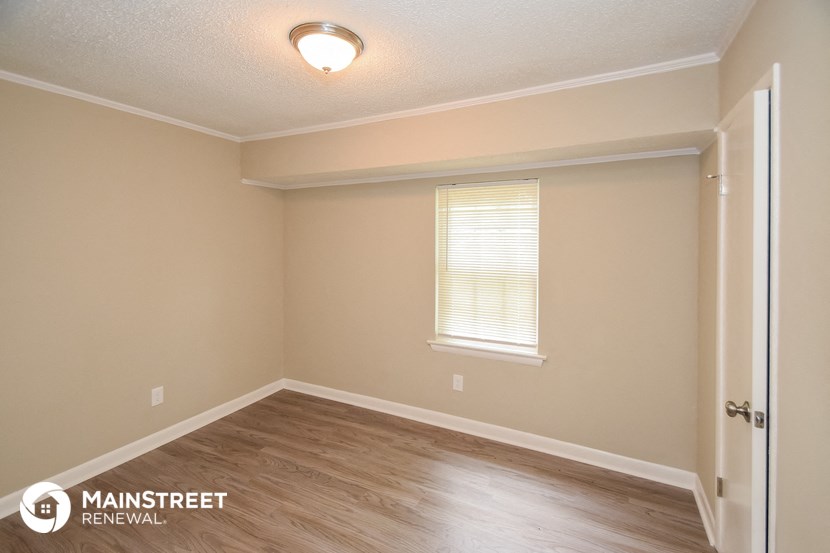 the upstairs bedroom with hardwood flooring and a window