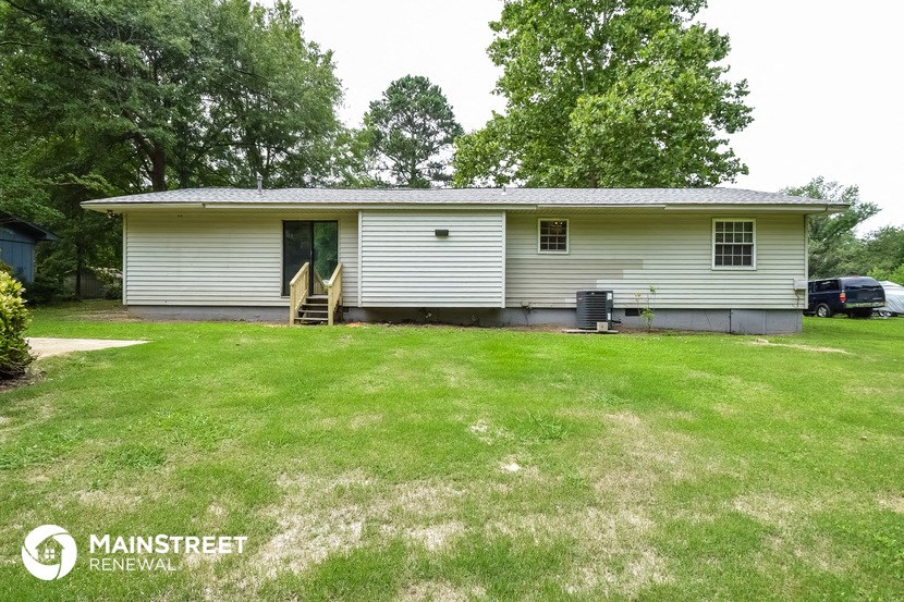 a small white house with a green lawn and trees