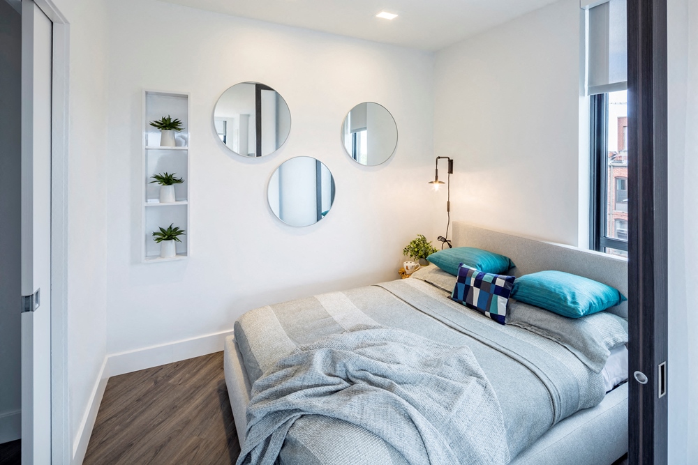 a bedroom with a bed and three mirrors on the wall