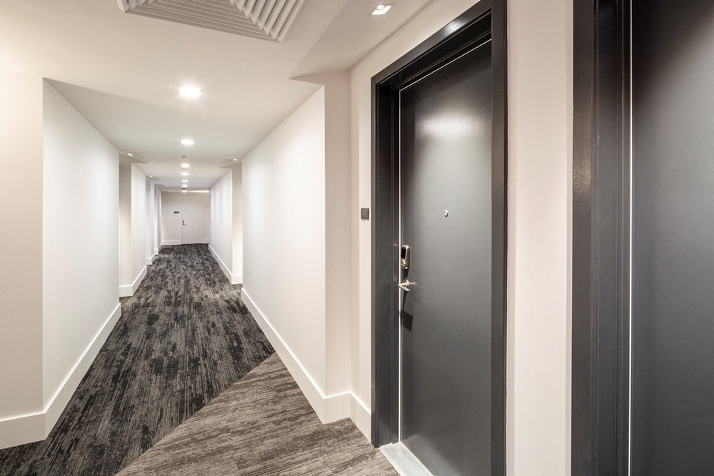 a corridor in a building with black doors and white walls
