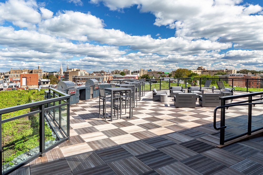 a rooftop terrace with tables and chairs and a city in the background