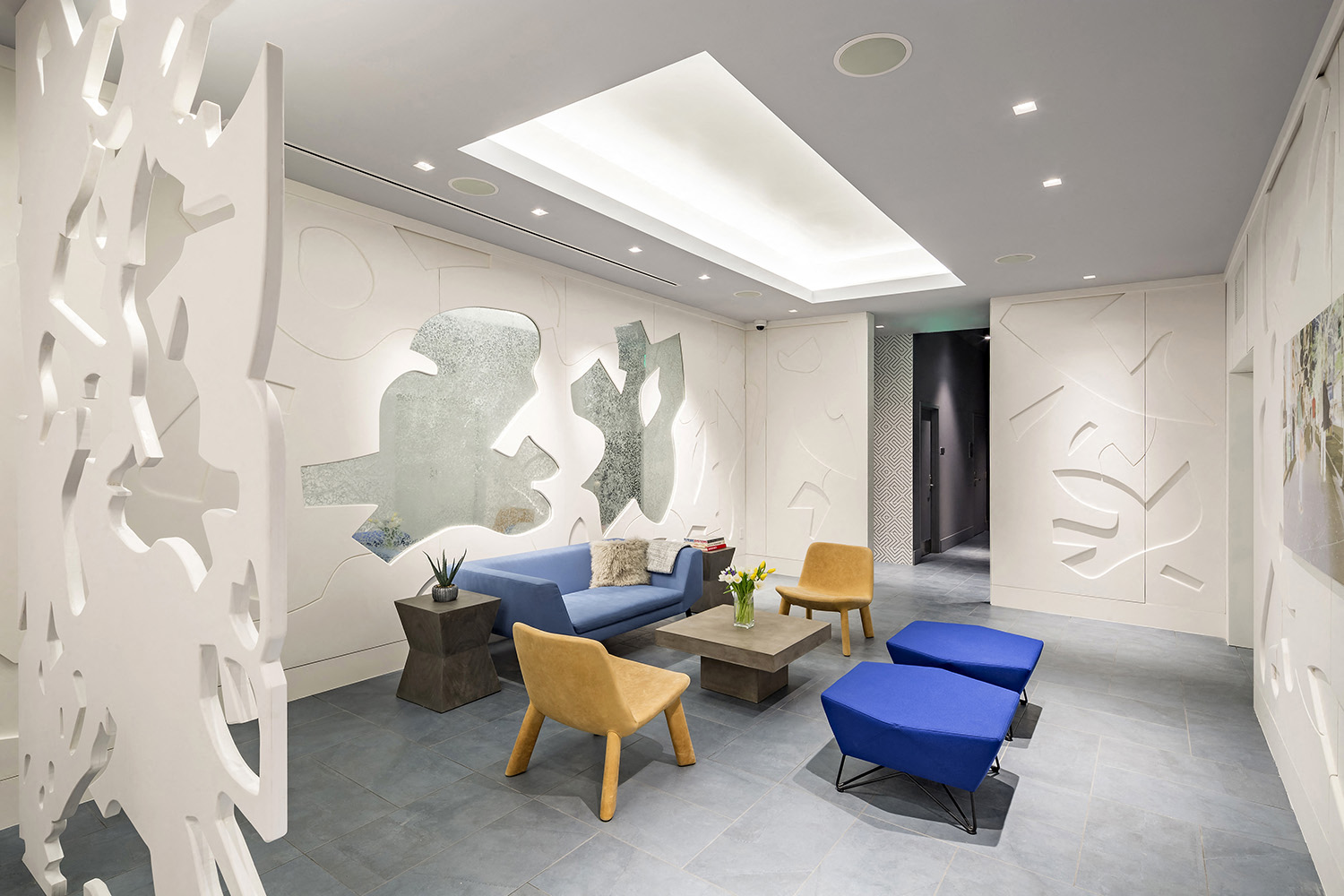 a living room with blue furniture and a mural on the wall